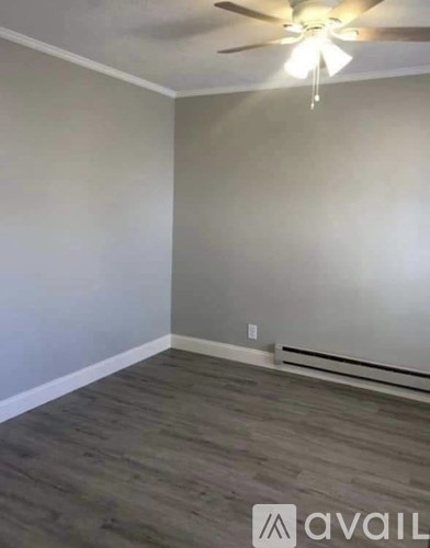 A room with a ceiling fan and wooden flooring.