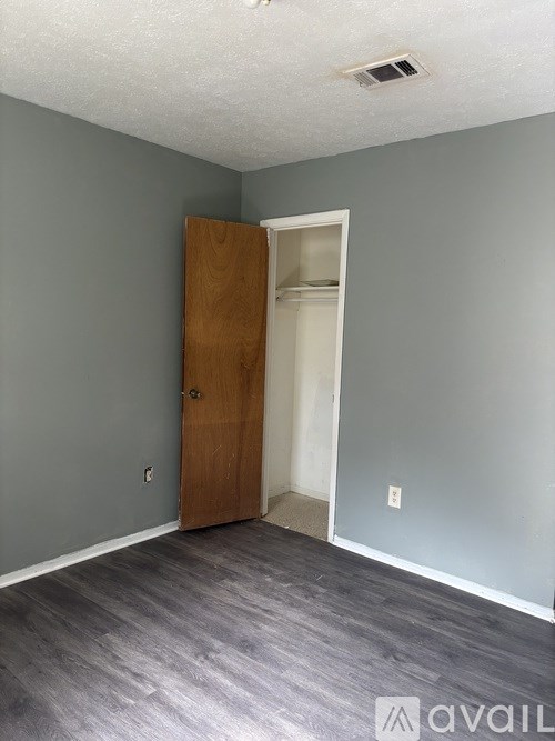 A room with a wooden door and grey walls.