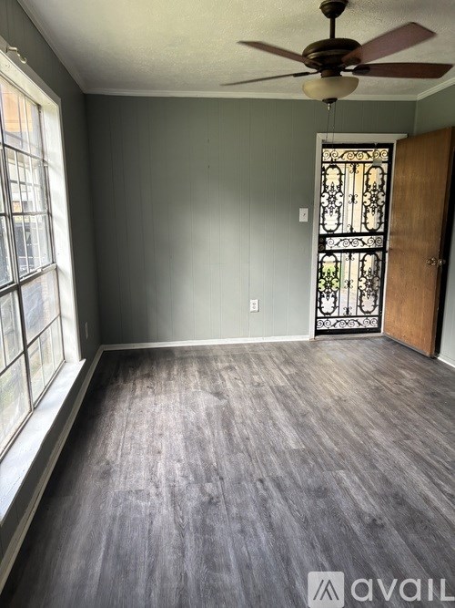 A room with a ceiling fan and a door with a stained glass window.