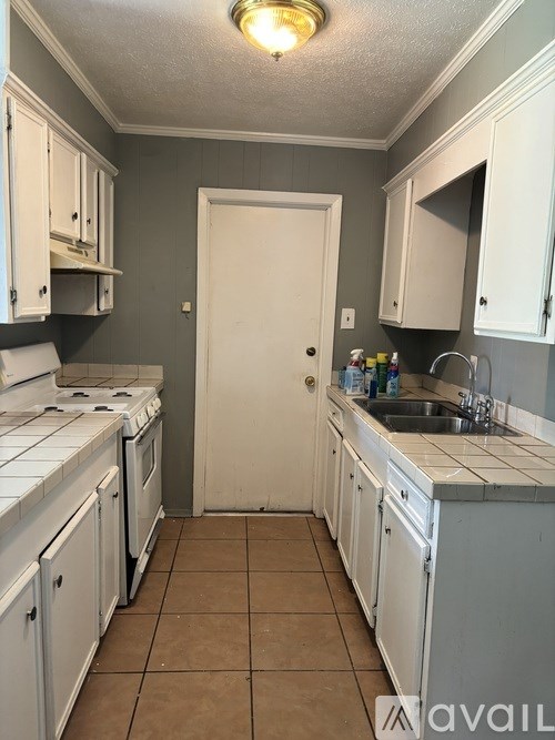 A kitchen with white cabinets and a white door.