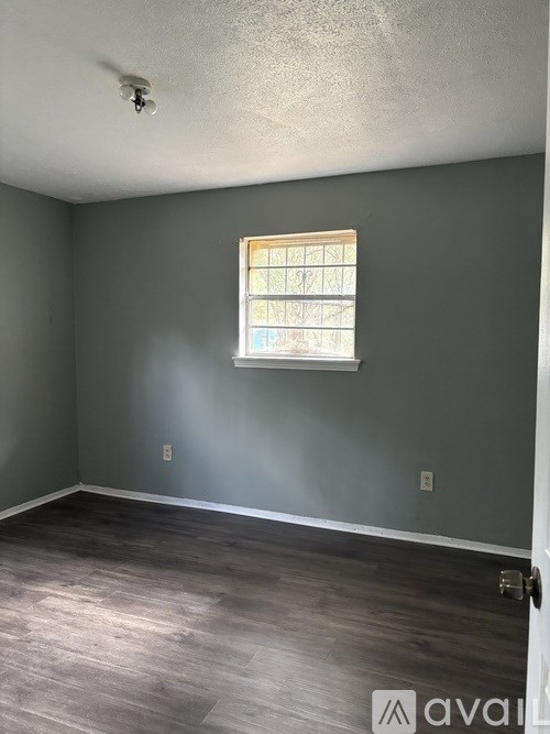 A room with a window and wooden flooring.