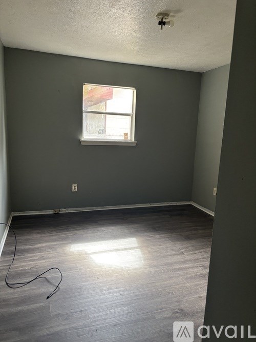A room with a window and a wooden floor.