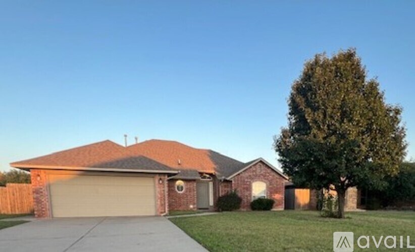A house with a garage and a tree in front of it.