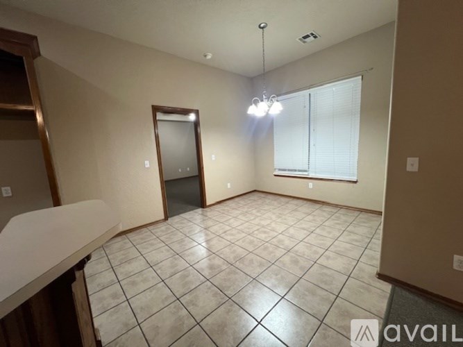 A spacious room with tiled flooring and a window with blinds.