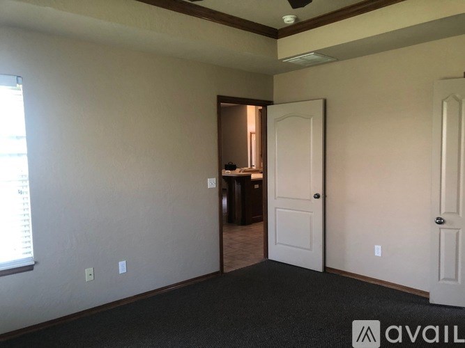 A room with a carpeted floor and two doors.