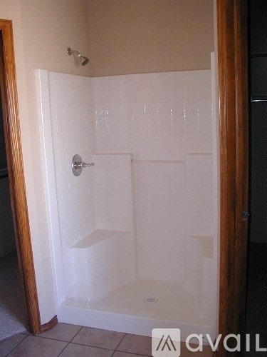 A white tiled shower with a door and a mat on the floor.