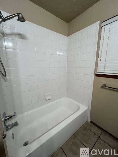 A white bathtub with a shower head attached to the wall.