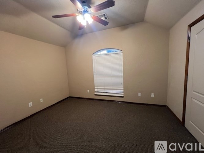 A room with a ceiling fan and a window with blinds.
