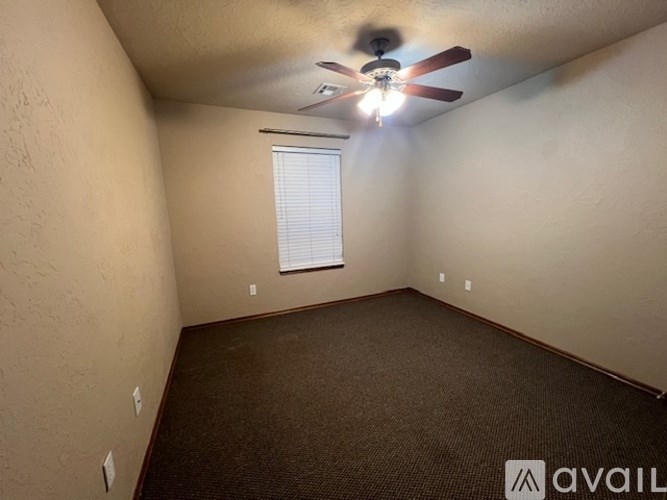 A room with a ceiling fan and a window with blinds.