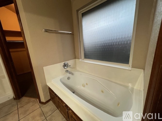 A white bathtub with a window above it in a bathroom.