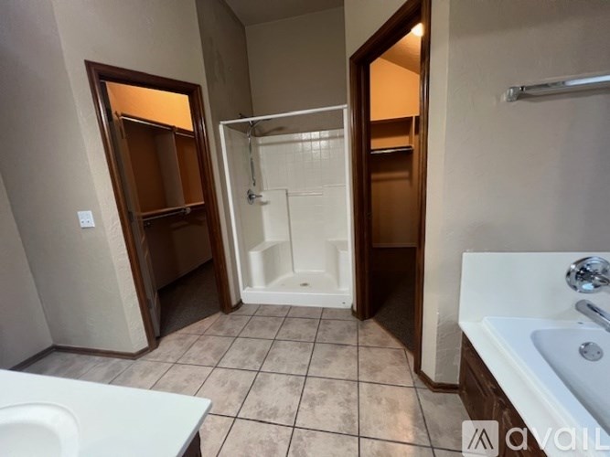 A bathroom with a white sink, a white toilet, a walk-in shower, and a wooden medicine cabinet.