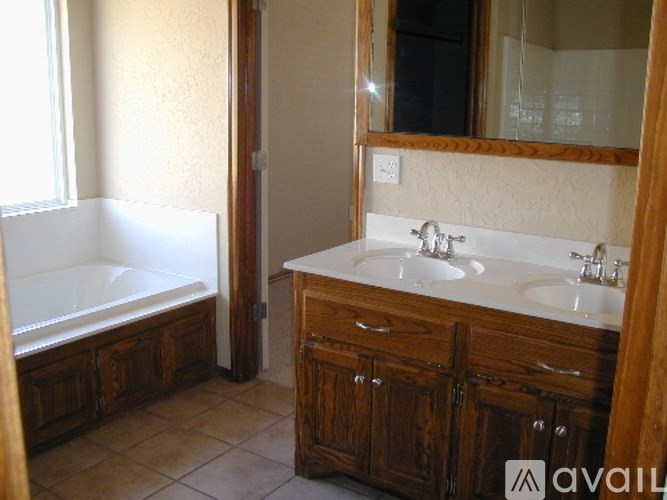 A bathroom with a tub, sink, and wooden cabinets.