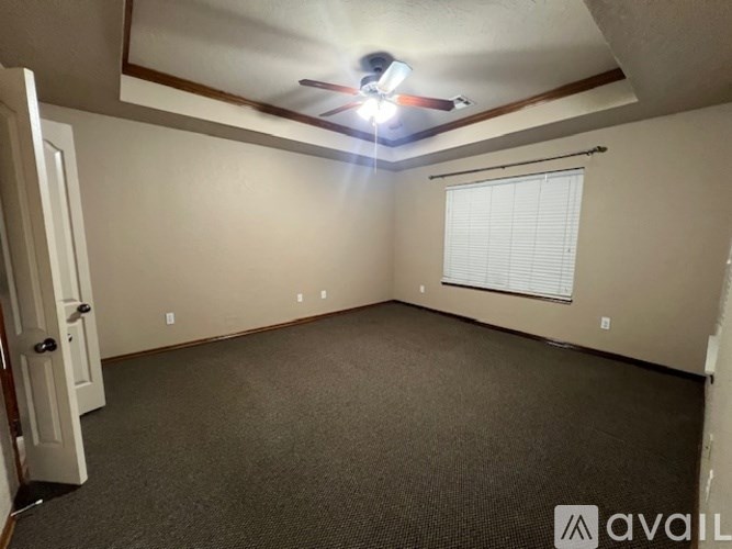 A room with a carpeted floor, a ceiling fan, and a window with blinds.