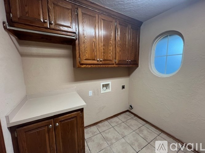 A kitchen area with wooden cabinets and a round window.