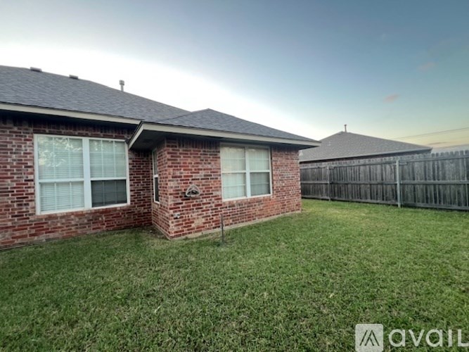 A house with a fence and a grassy yard is available for rent.