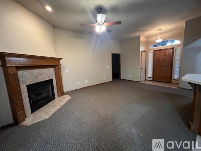 A living room with a fireplace and a ceiling fan.