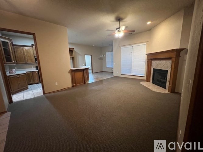 A spacious living room with a fireplace and a ceiling fan.