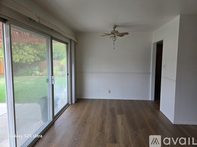 A room with a ceiling fan and sliding glass doors.