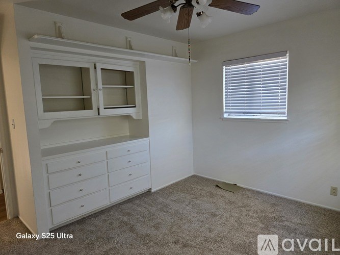 A room with a ceiling fan and a window with blinds.