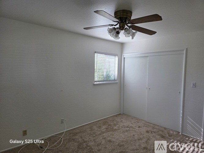 A room with a ceiling fan and a window with blinds.