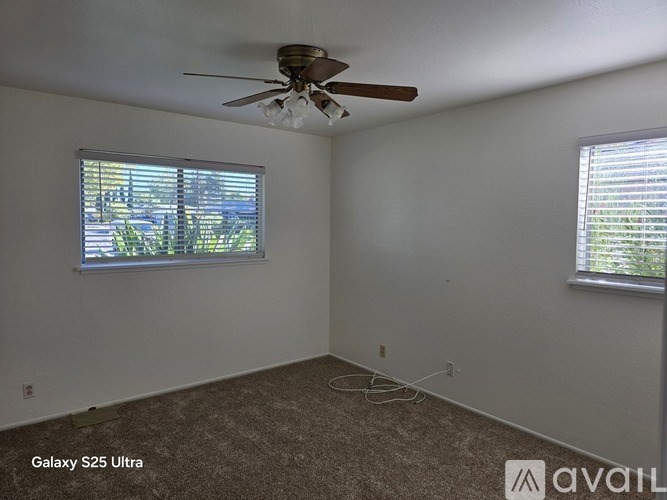A room with a ceiling fan and a window with blinds.