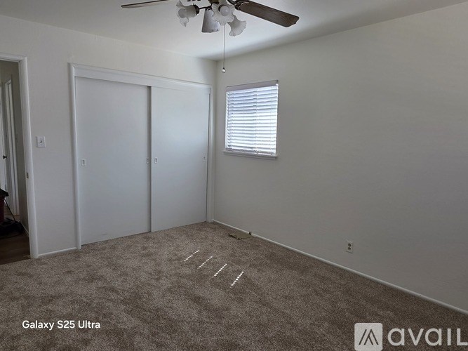 A room with a ceiling fan and two doors.