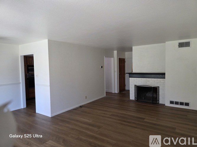A living room with a fireplace and wood flooring.