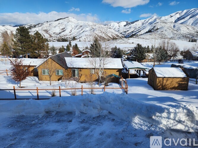 A snowy landscape with a wooden house and a mountain in the background.