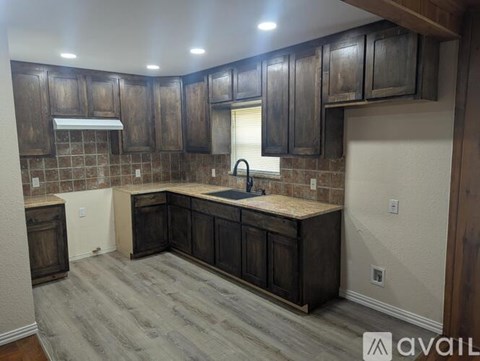 A kitchen with dark wood cabinets and a marble countertop.
