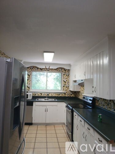 A kitchen with a black counter top and white cabinets.