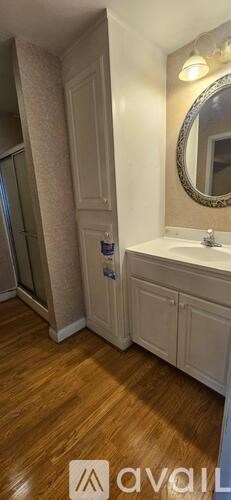 A bathroom with a wooden floor and a mirror above a sink.