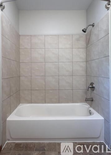 A white bathtub in a tiled bathroom.