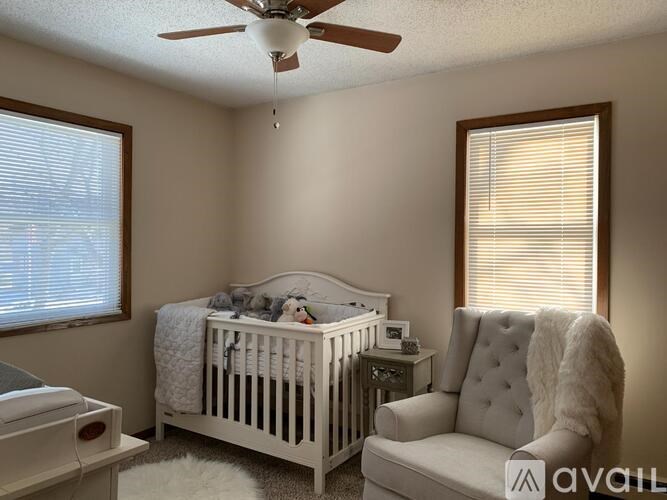 A baby's room with a white crib and a white chair.