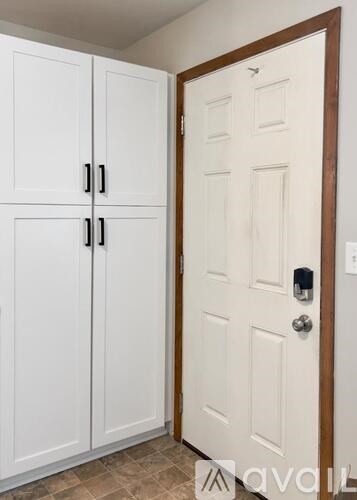 A white door with a black handle and a white cabinet with three doors and two handles.