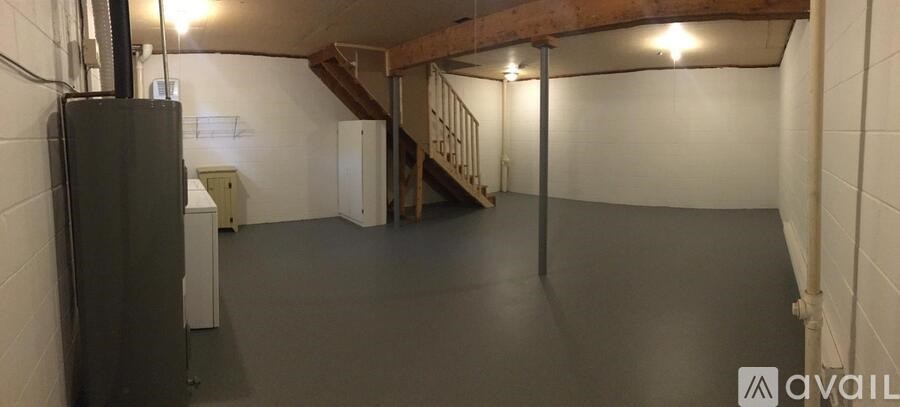 A spacious basement with a refrigerator and a staircase.