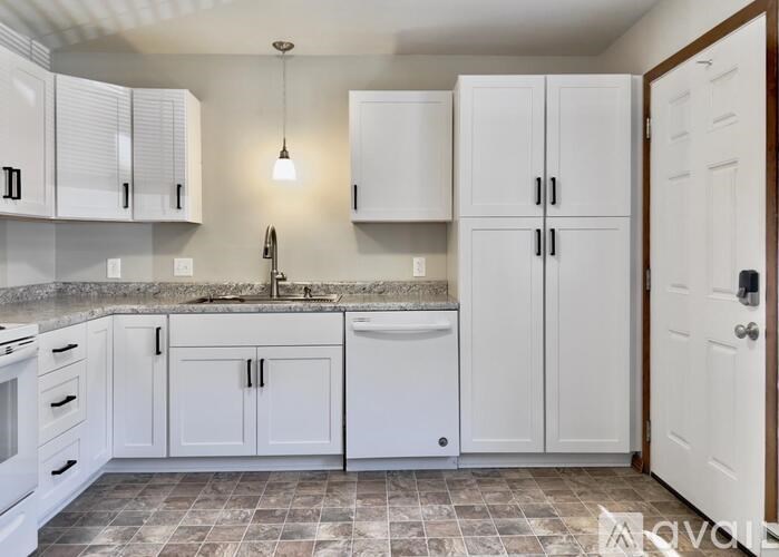 A kitchen with white cabinets and a tiled floor.