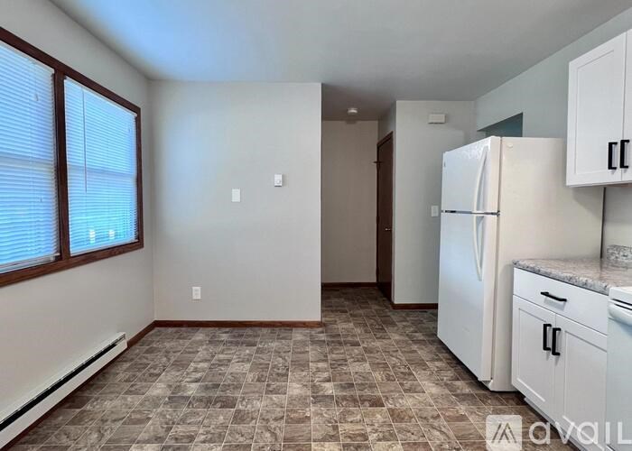 A kitchen area with a refrigerator, cabinets, and a tiled floor.