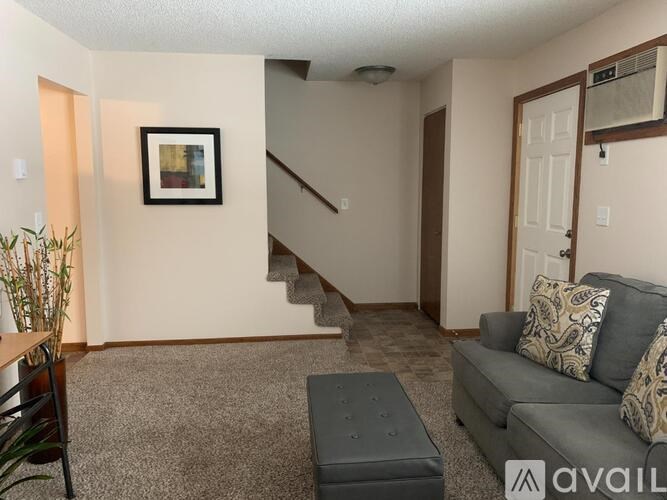 A living room with a grey couch and a painting on the wall.