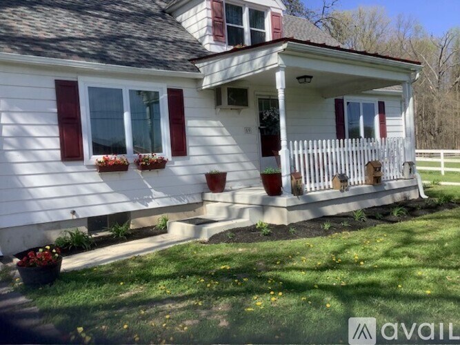 A white house with red shutters and a porch.