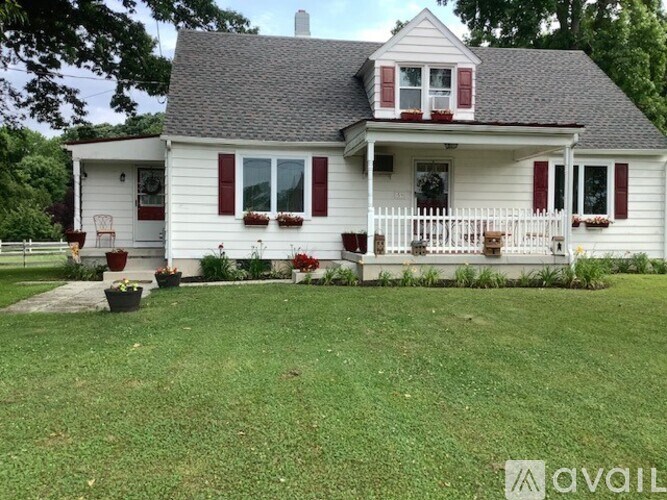 A white house with red shutters and a black roof.