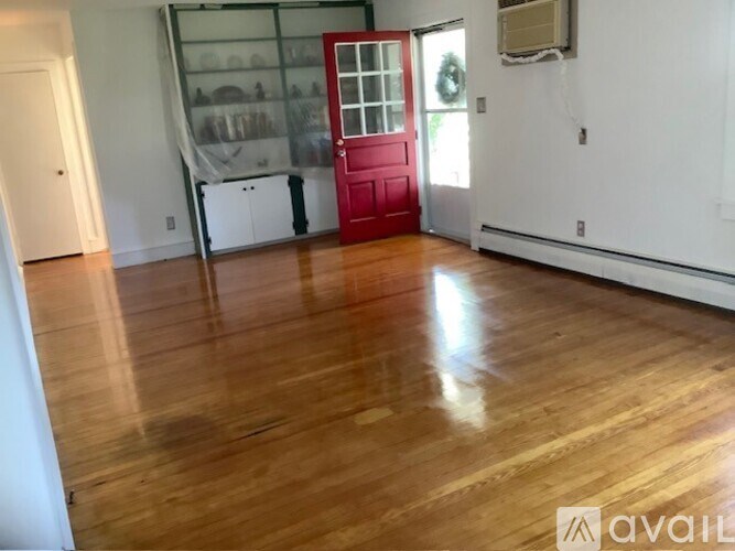 A room with a wooden floor and a red door.