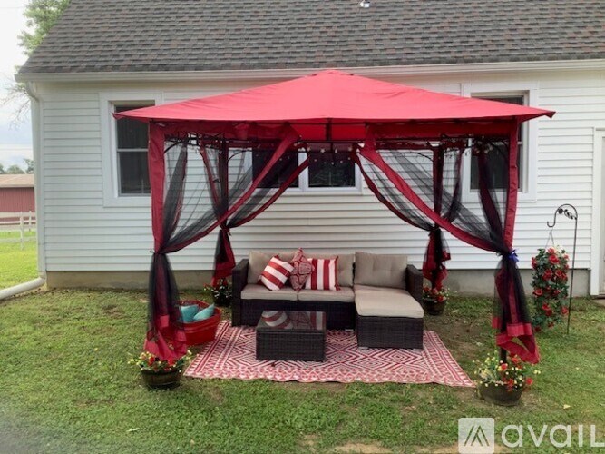 A red canopy with black drapes is set up in a backyard.