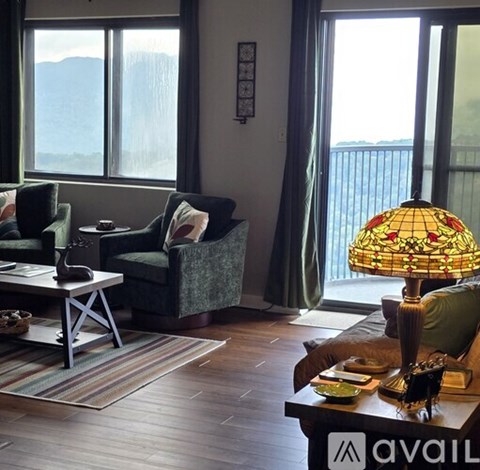 A living room with a couch, armchair, and a coffee table with a lamp on it.