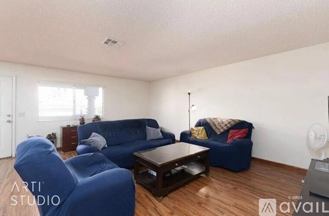 A living room with blue couches and a wooden floor.