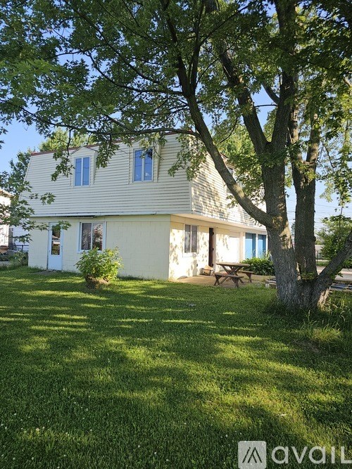 A house with a lawn and a tree in front of it.