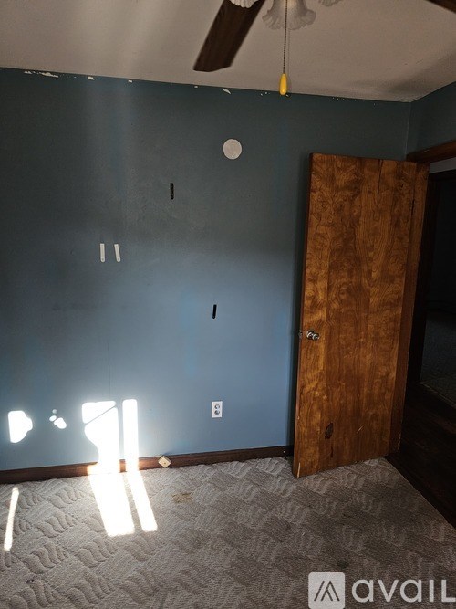 A room with a ceiling fan and a door.