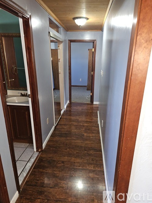 A long hallway with wood floors and white walls.