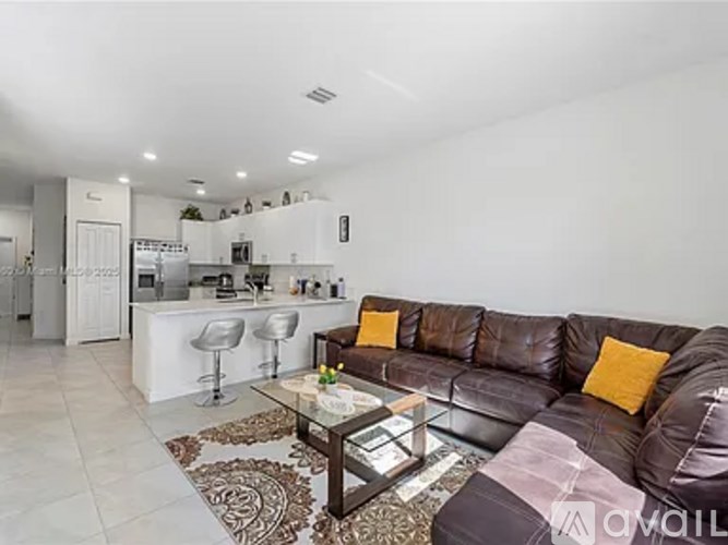 A brown couch with a glass table in front of it.