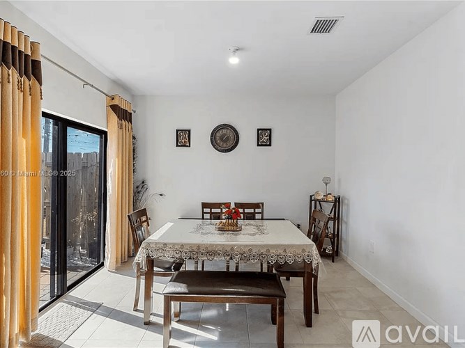 A dining room with a table set for two and a view of a balcony.