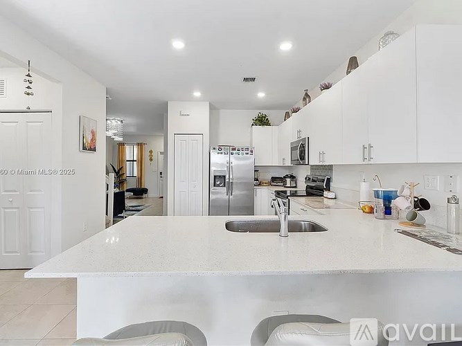 A kitchen with white cabinets and a white island with a sink.
